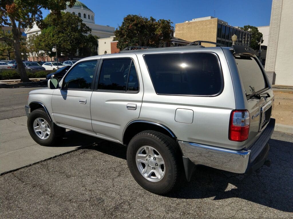 Silver SUV parked in an outdoor lot under a bridge.