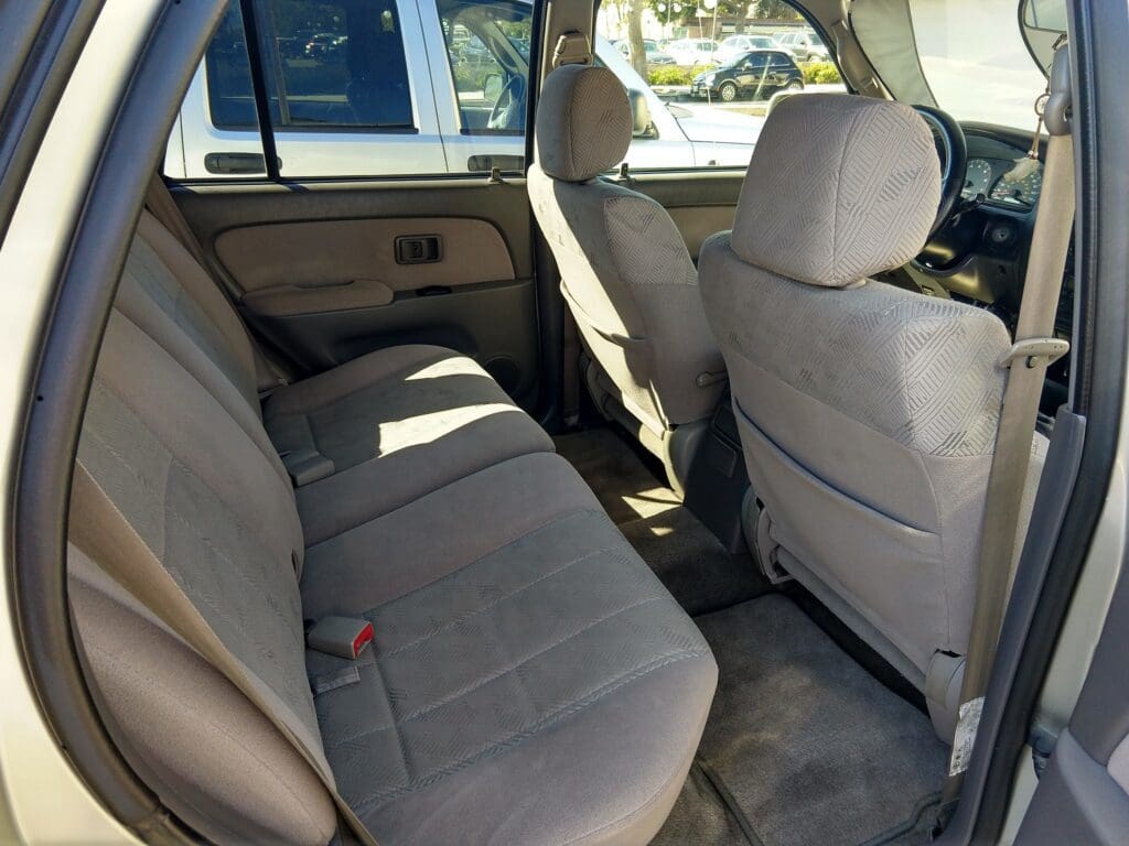 Clean beige interior of a car's back seat with fabric upholstery.