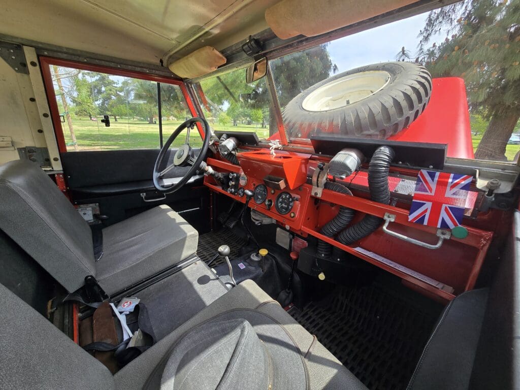 Interior of a vintage red truck with a Union Jack dashboard decoration.