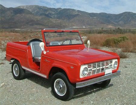 Classic red vintage off-road vehicle parked outdoors.