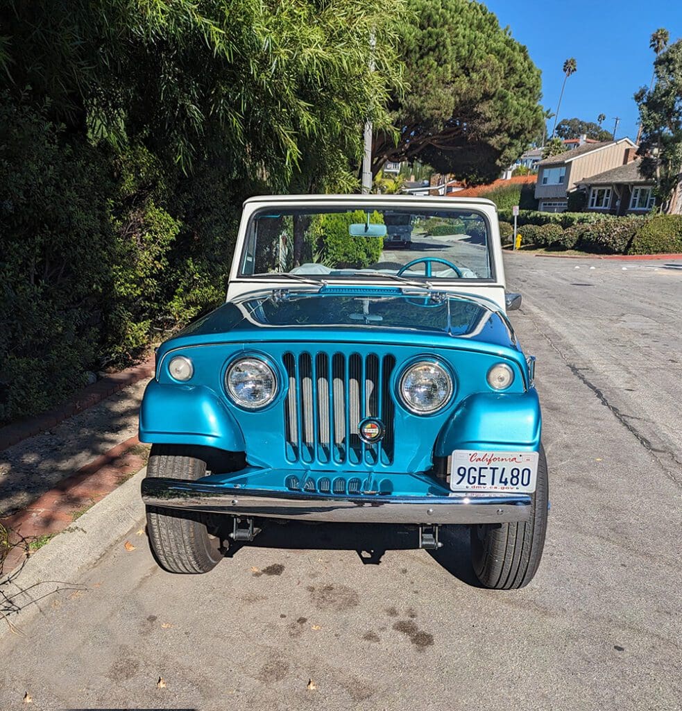 Vintage blue convertible parked on a sunny street.