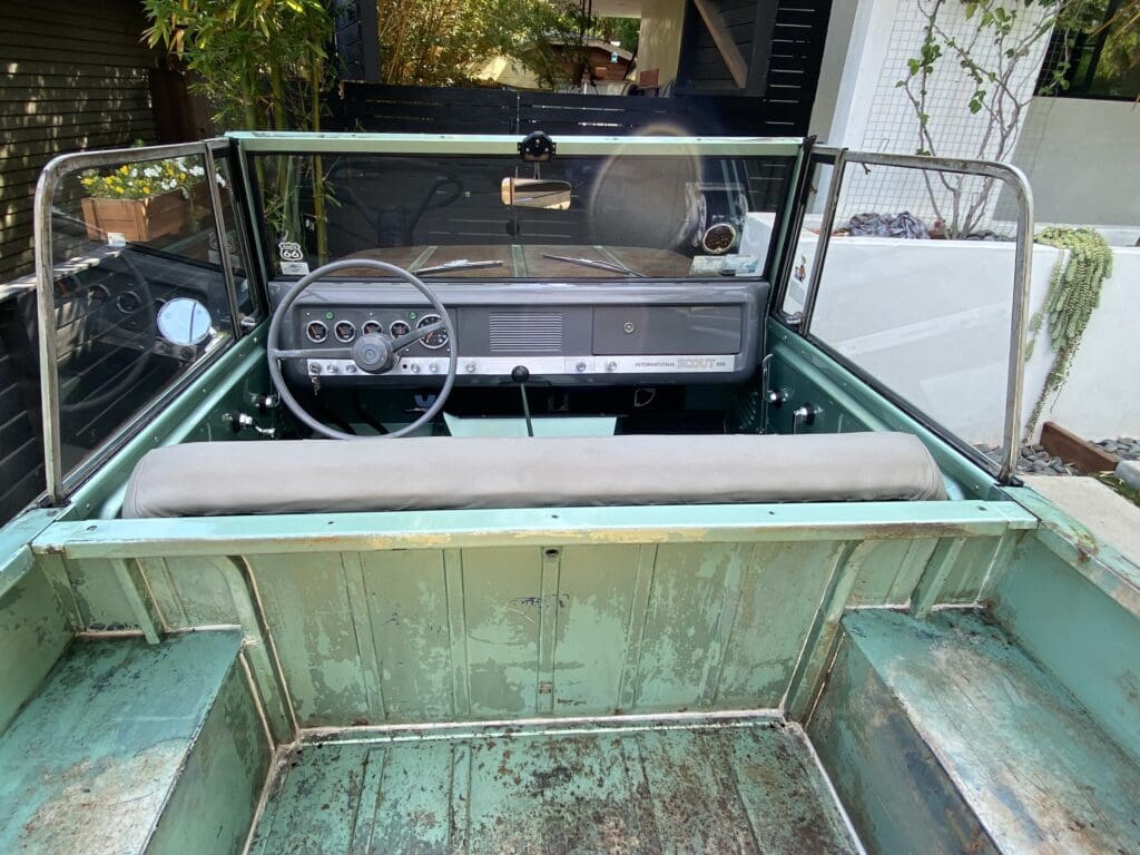 Interior view of a vintage green car with a simple dashboard and steering wheel.