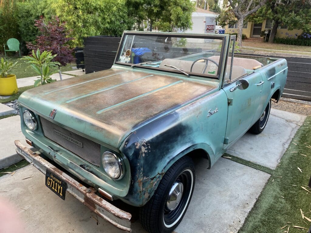 Rusty vintage convertible parked on a driveway.