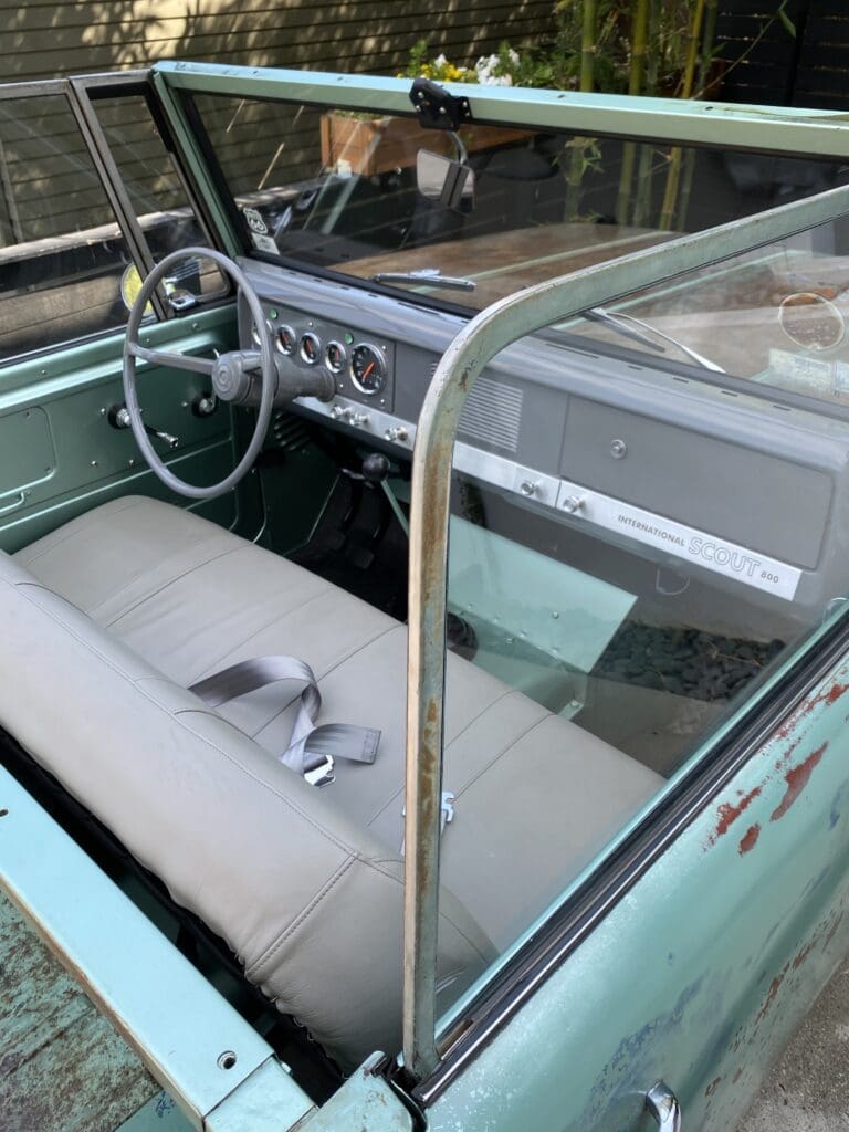 Interior view of a vintage convertible car with bench seating and simple dashboard.