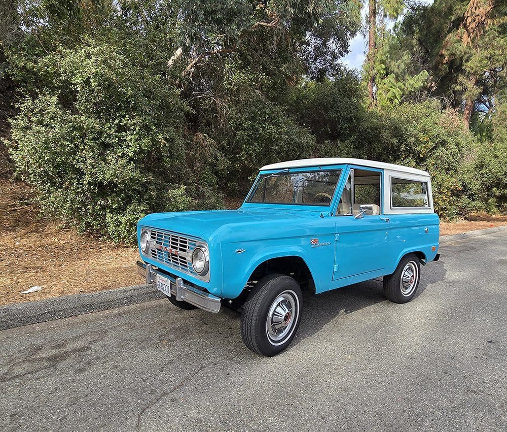 Vintage blue off-road SUV parked on a quiet road.