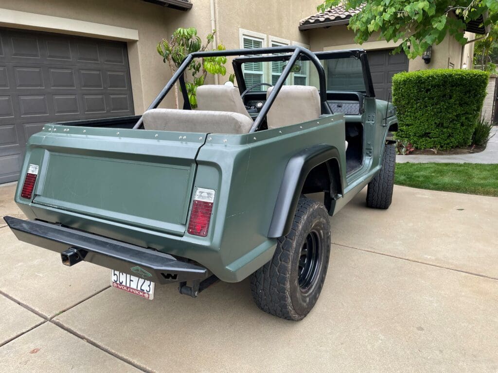 Vintage off-road vehicle parked on a driveway with open doors and roof.