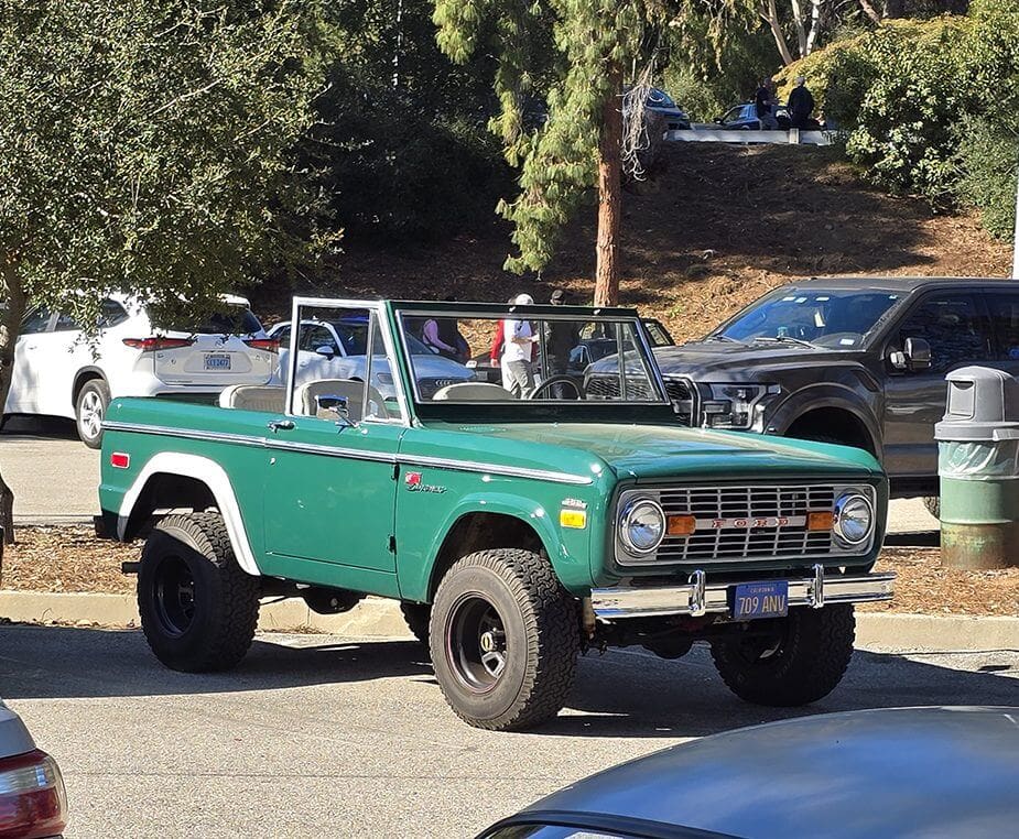 Classic green Ford Bronco parked outdoors in a sunny area.