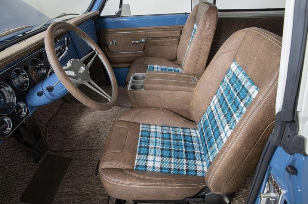 Vintage car interior with brown leather and blue plaid seats.