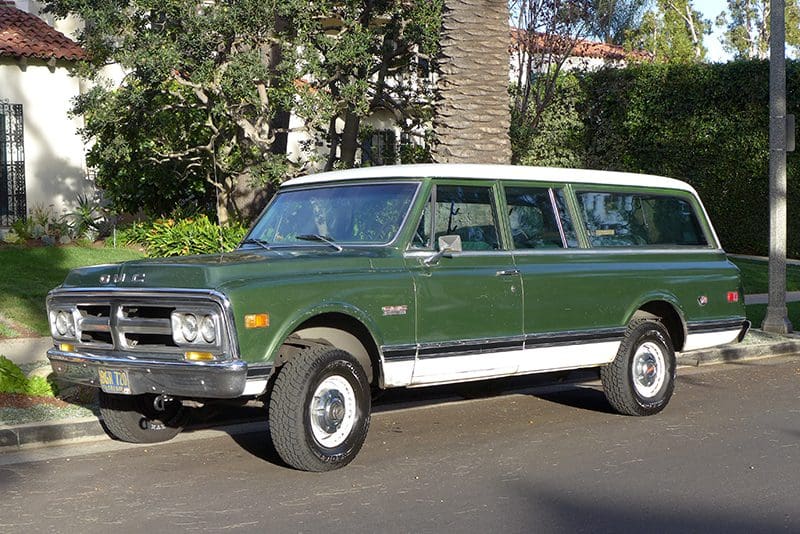 Classic green and cream vintage SUV parked on a street.