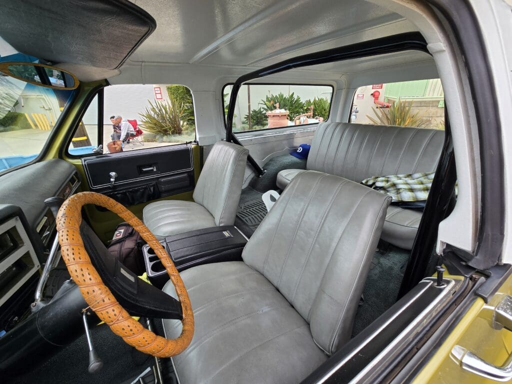Interior of a classic car with leather seats and wooden steering wheel.