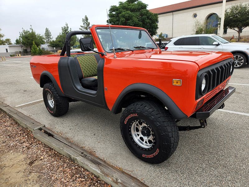 Classic orange off-road vehicle with open doors and rugged tires.
