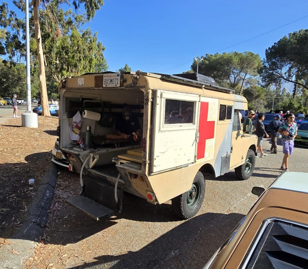 Vintage military ambulance parked outdoors under trees.