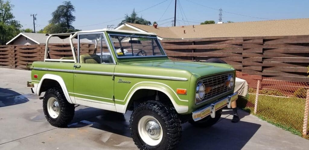 Classic green Ford Bronco parked outdoors on a sunny day.
