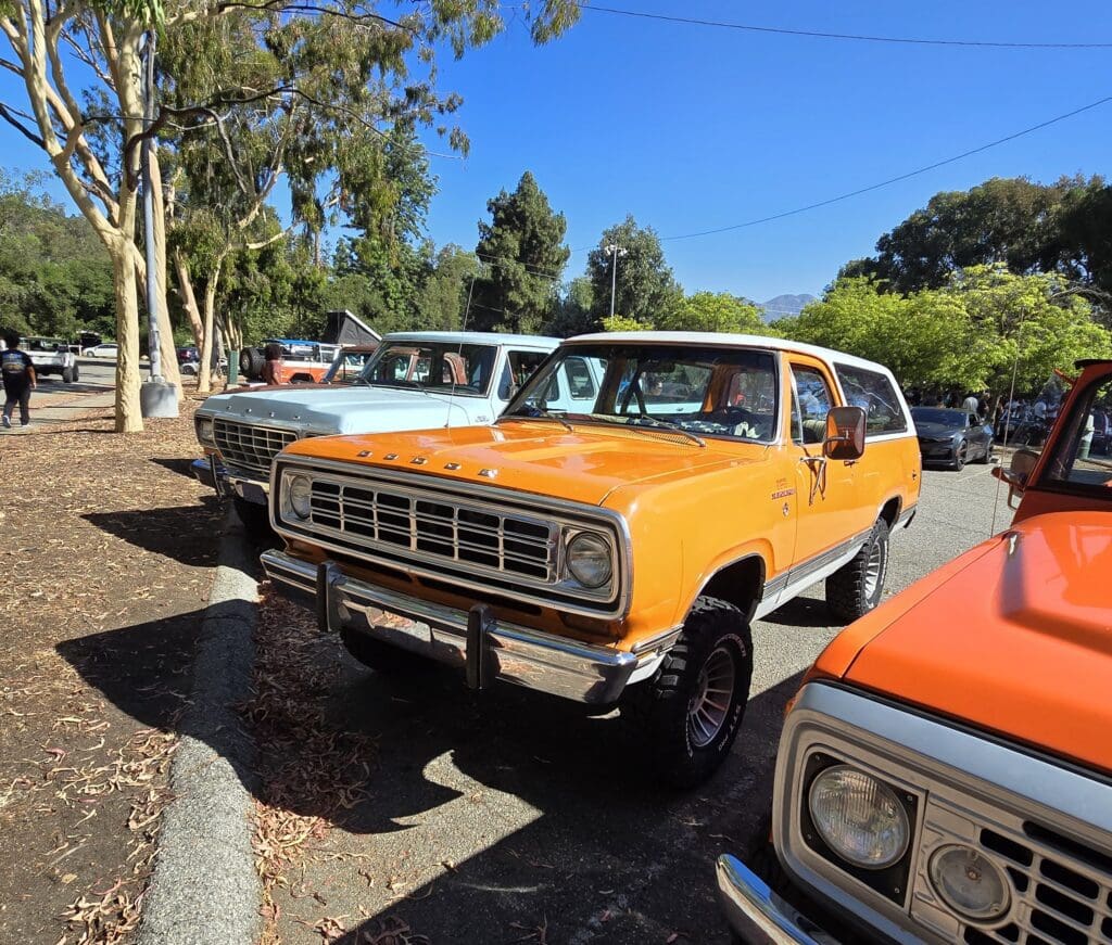 Classic yellow off-road vehicle parked among other vintage cars on a sunny day.
