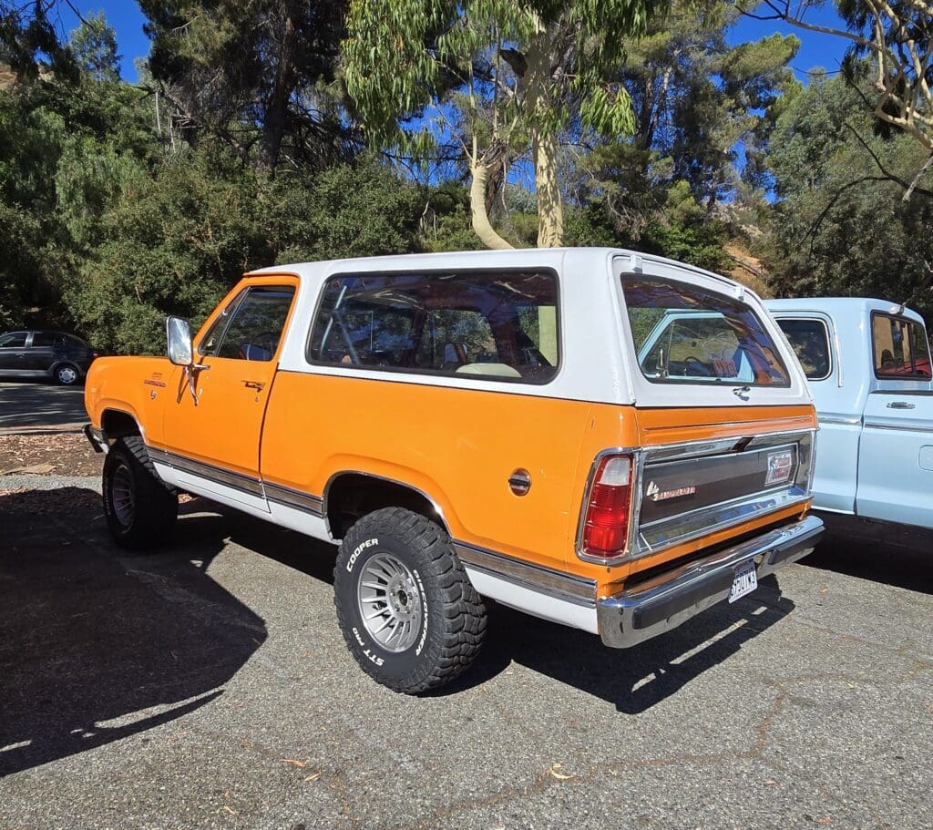 Vintage orange and white SUV parked outdoors on a sunny day.