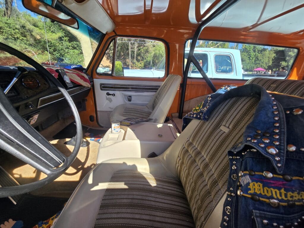 Interior of a vintage car with striped fabric seats and wooden dashboard.