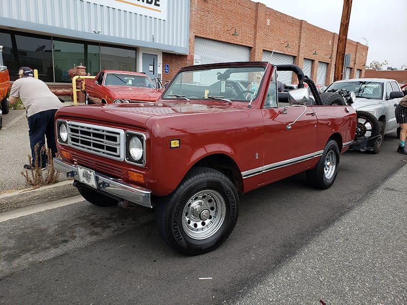 Classic red Ford Bronco convertible parked on a street.