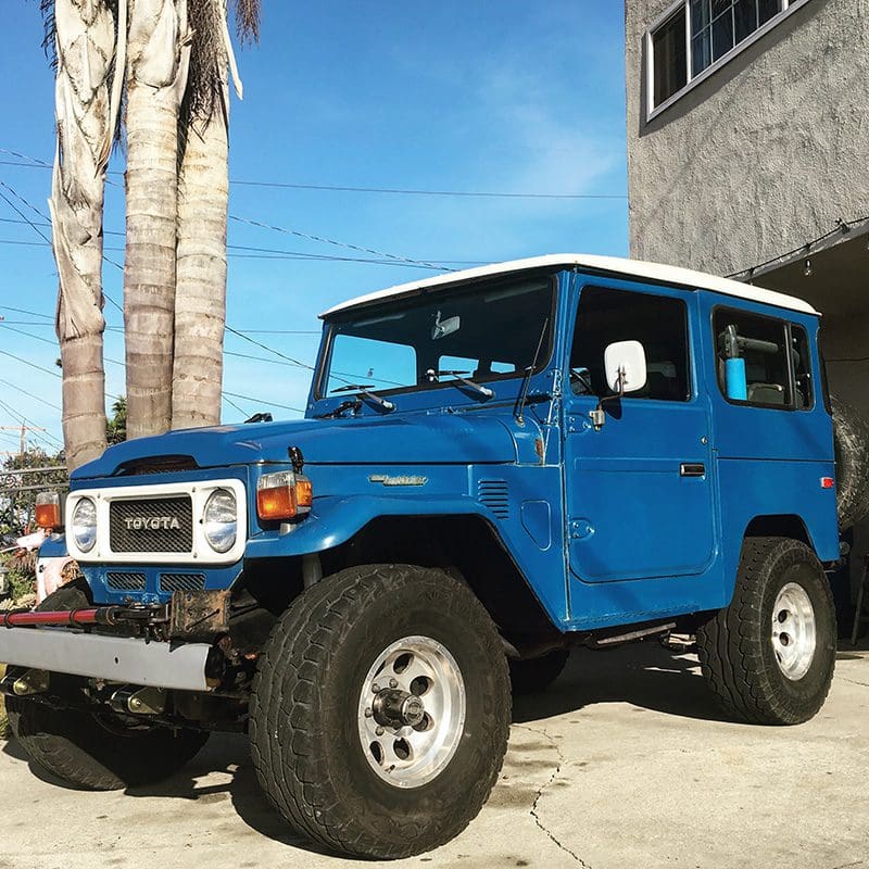 Classic blue off-road vehicle parked outdoors under a clear sky.