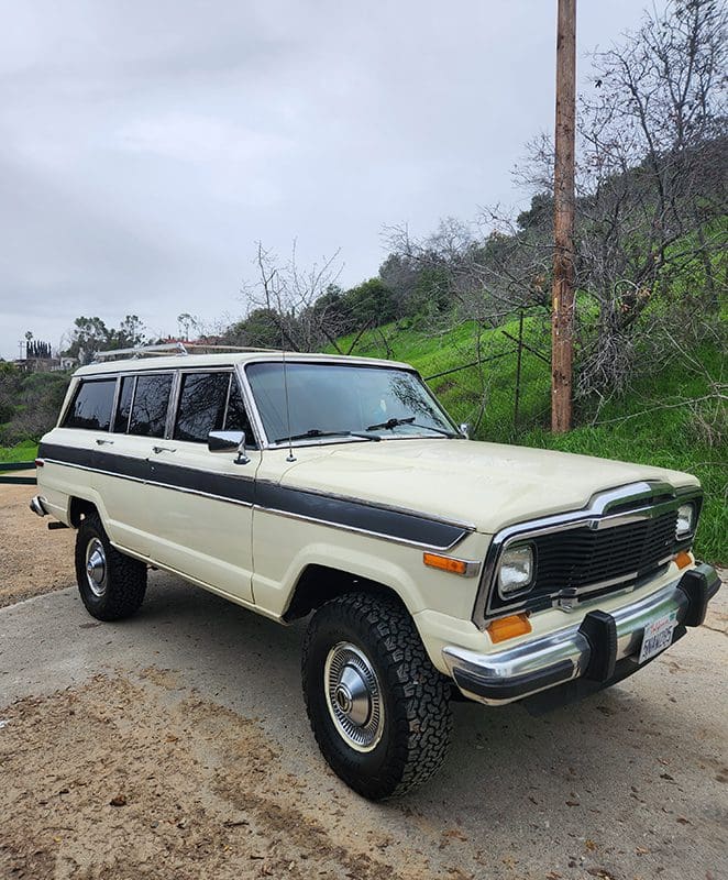 Classic white Jeep Wagoneer parked on a rural road.