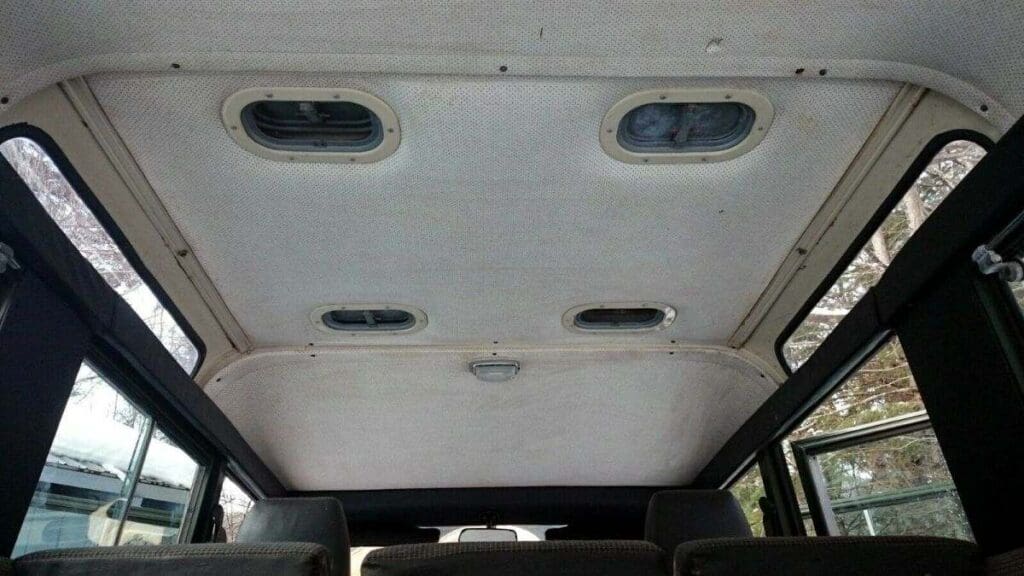 Interior roof of a vehicle with small windows and ventilation compartments.