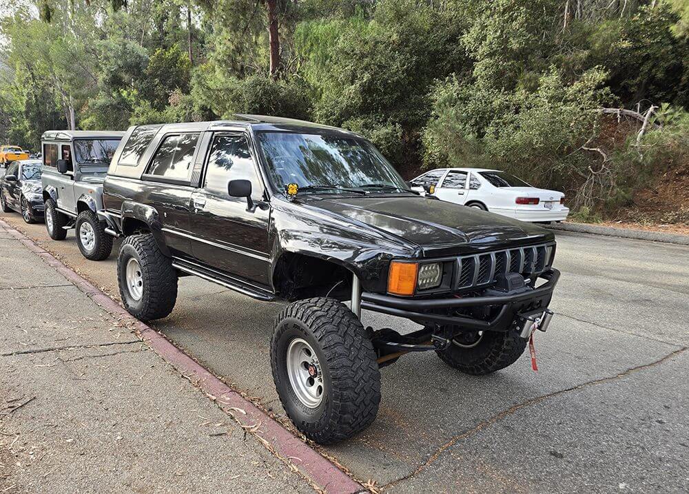 Lifted black SUV with off-road tires parked beside a curb.