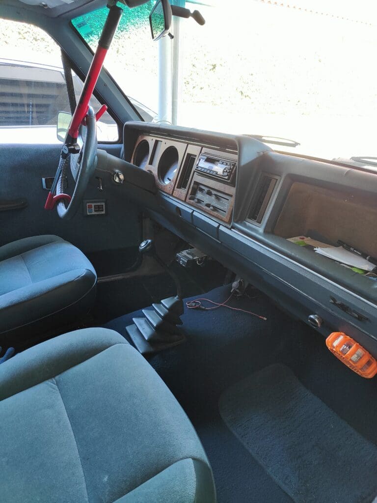 Interior of an older vehicle showing the dashboard and front seats.