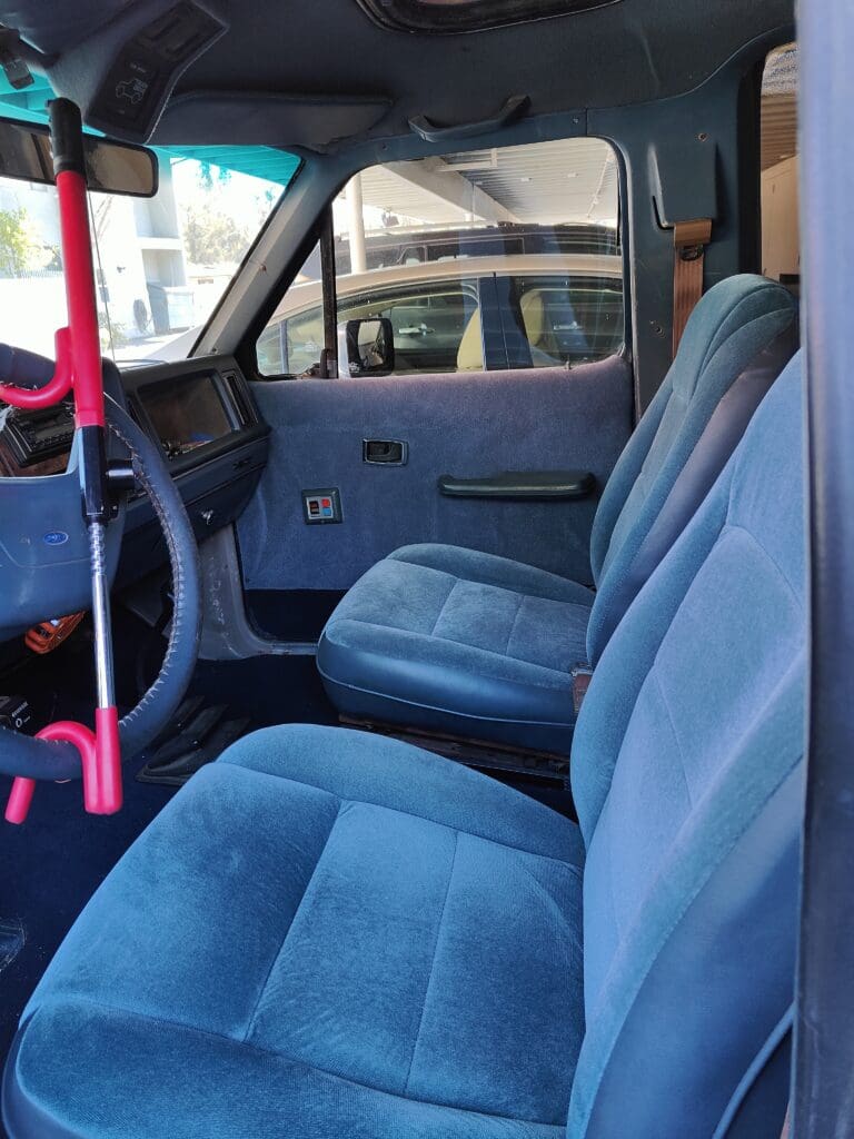 Interior of a car with blue fabric seats and manual controls.