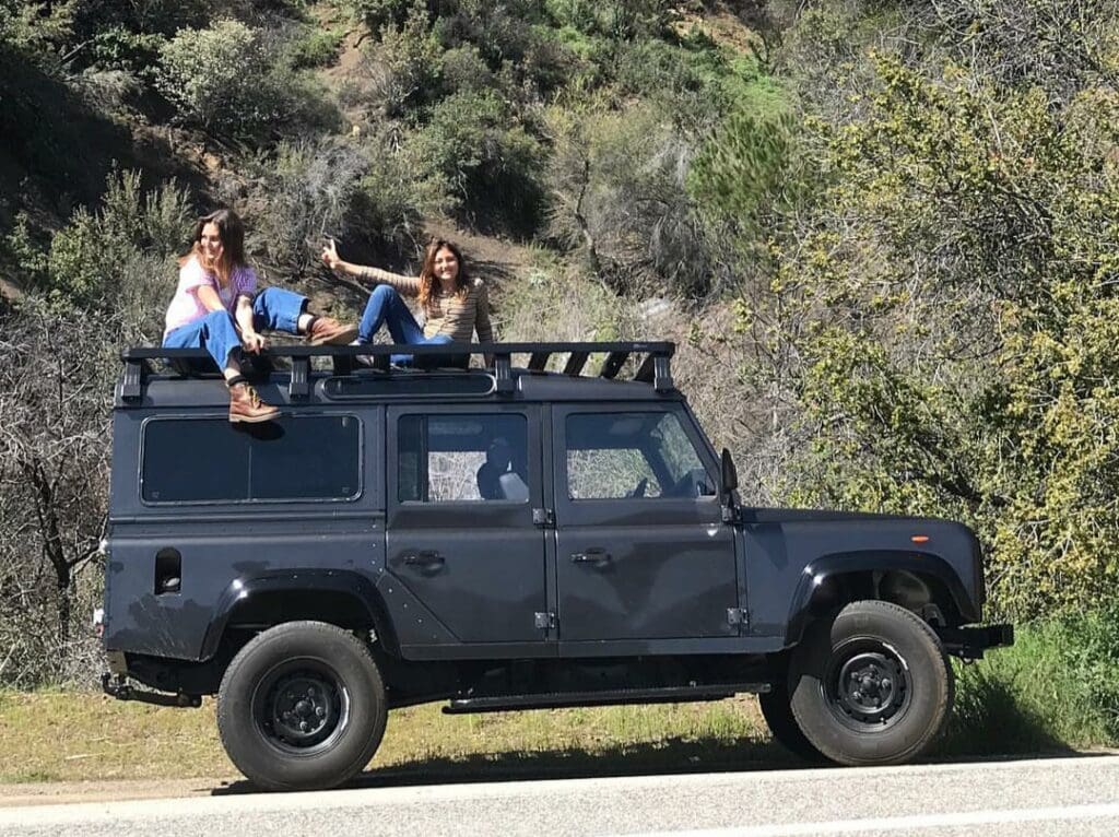 Two people sitting on a black off-road vehicle in a natural setting.