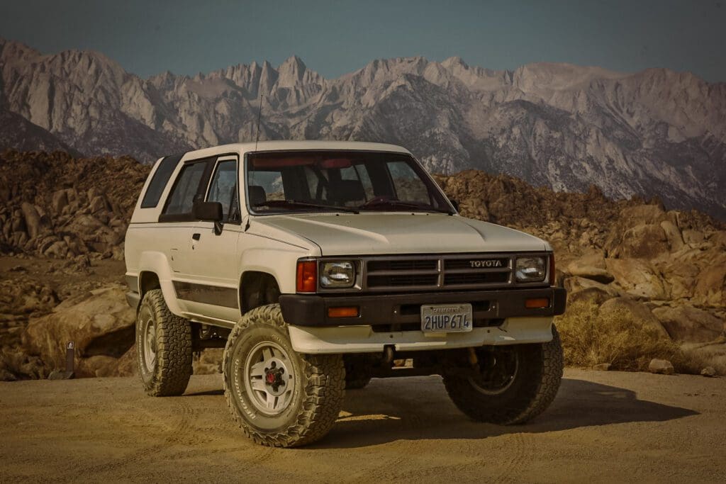 A white off-road SUV parked with mountains in the background.