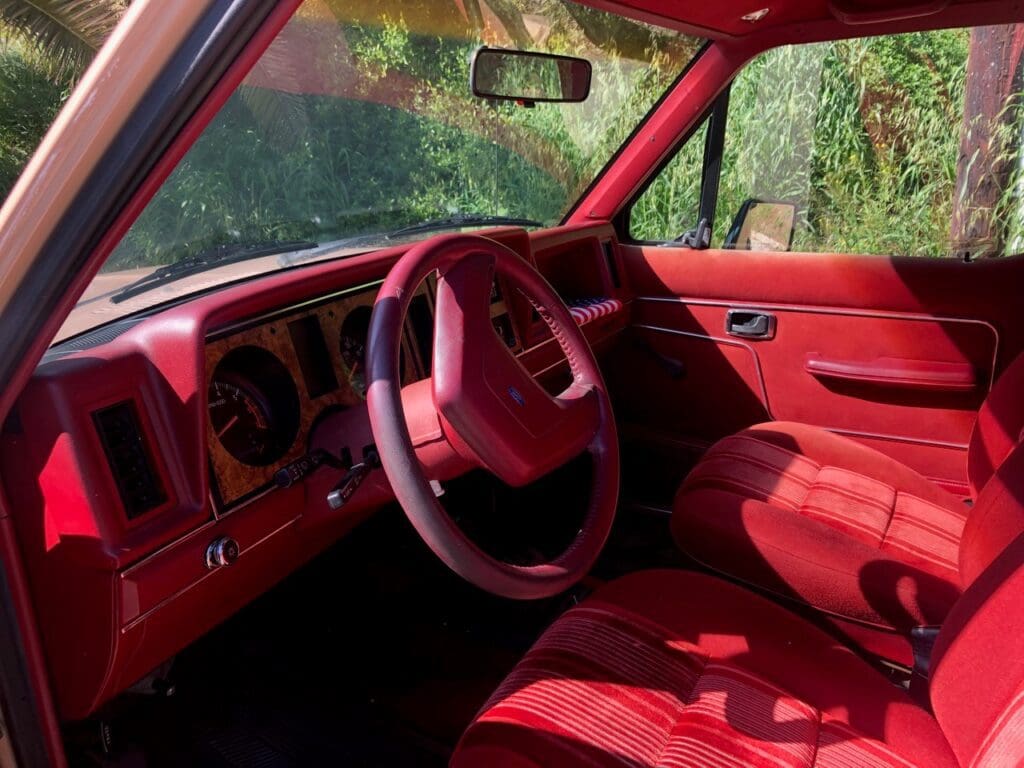 Vintage car interior with vibrant red upholstery and classic steering wheel.