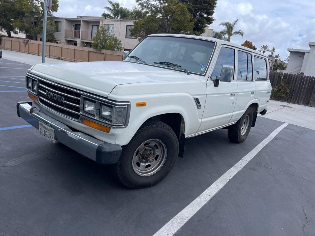 Classic white SUV parked on the street under a partly cloudy sky.