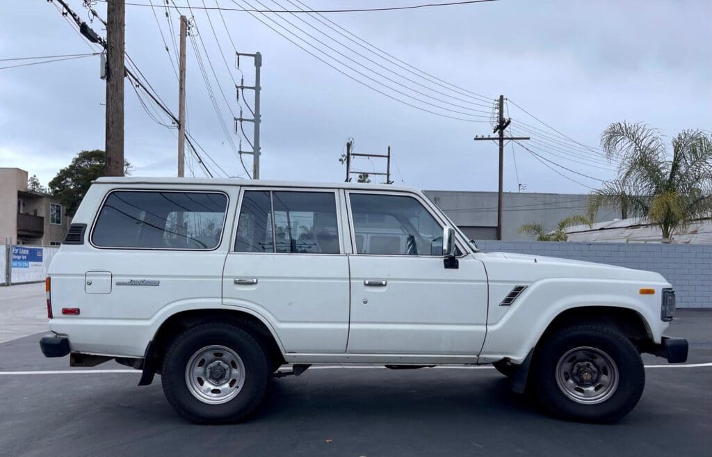 White classic SUV parked outdoors on a cloudy day.