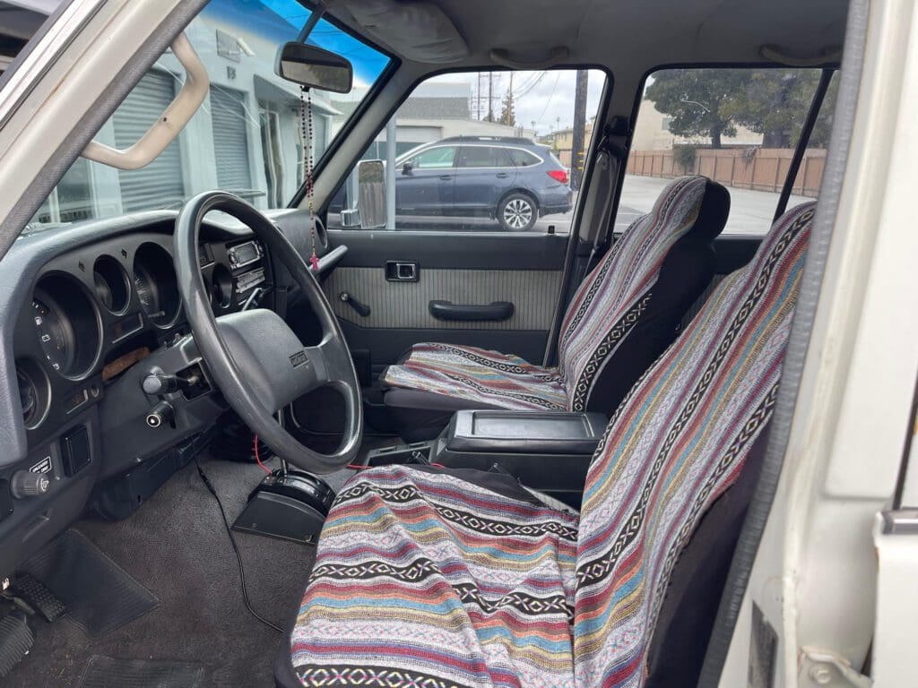 Interior view of a car showing front seats with striped covers and steering wheel.