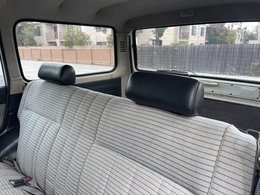 Interior of a classic car with striped fabric seats and black headrests.