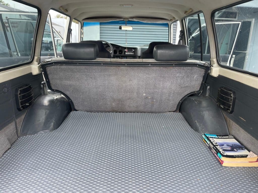 Empty car trunk with grey carpet and rear seats.