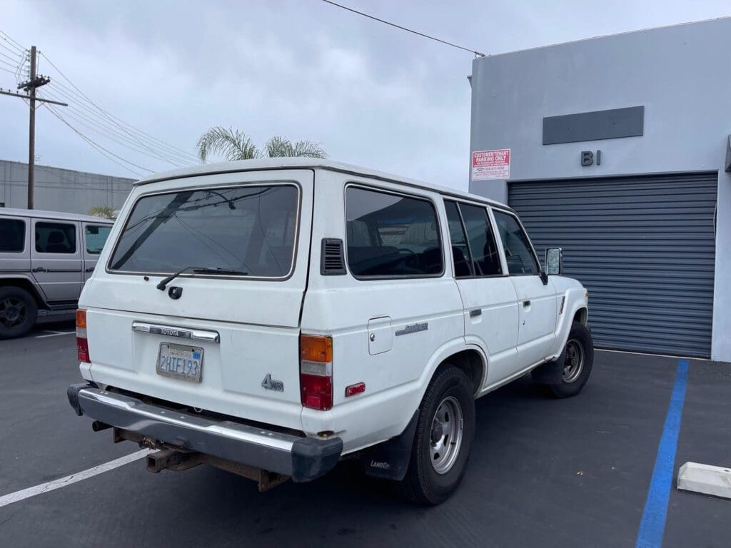 White Toyota Land Cruiser parked outside a building on a cloudy day.