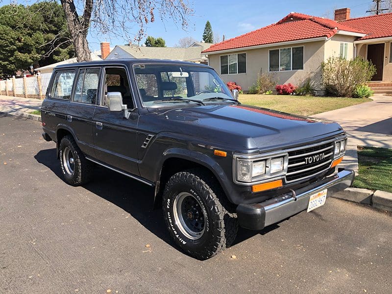 Classic gray SUV parked on a driveway near houses.