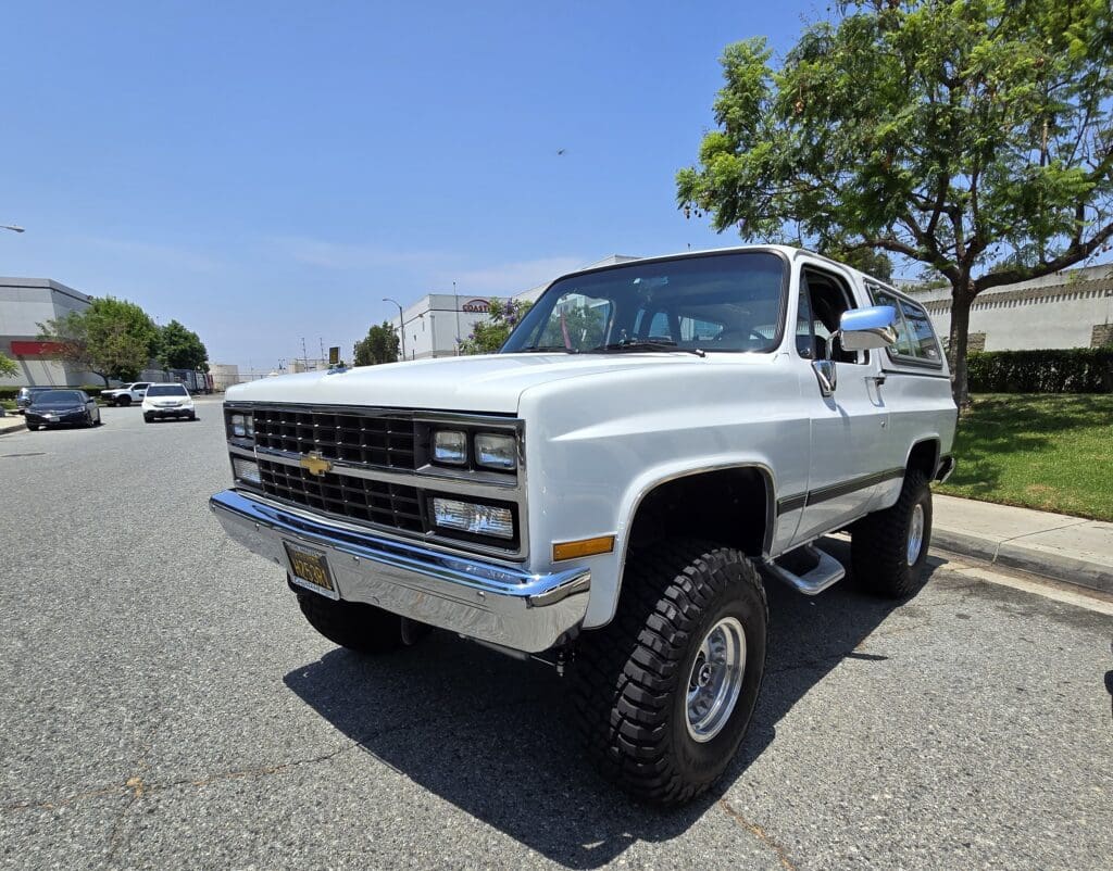 A classic white lifted truck parked on a sunny street.