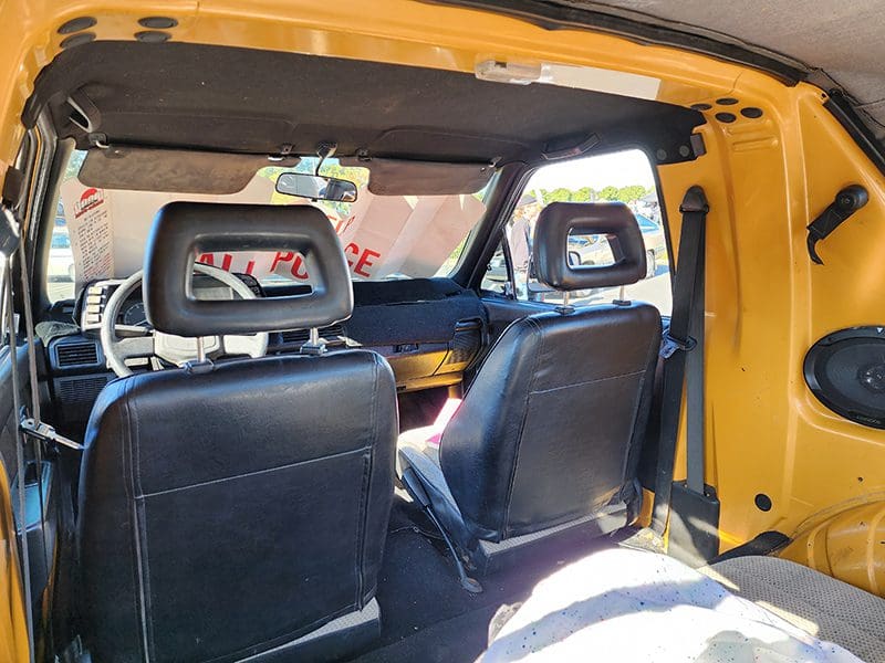 Interior view of a vehicle showing black seats and a yellow frame.