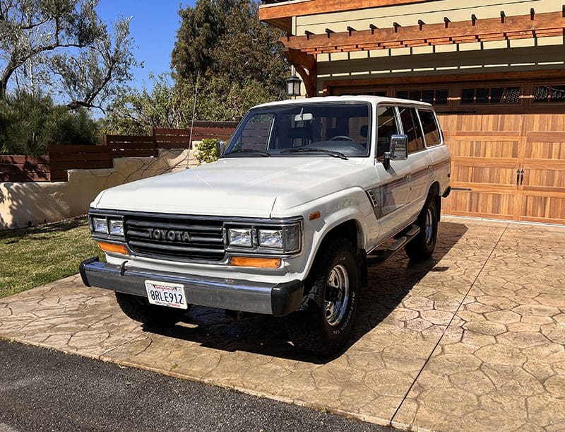 Classic white Toyota 4Runner parked in a driveway on a sunny day.