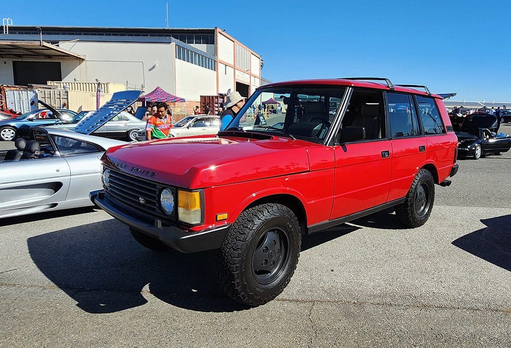 Classic red Range Rover parked outdoors on a sunny day.