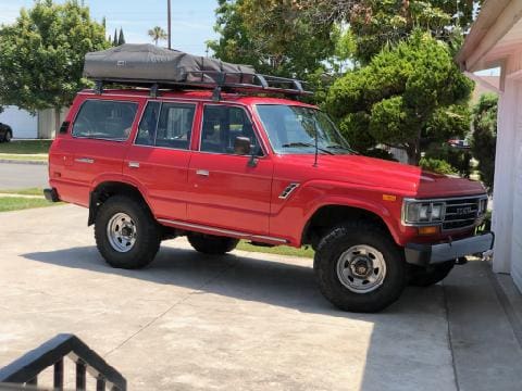 Red off-road SUV equipped with roof storage and accessories.
