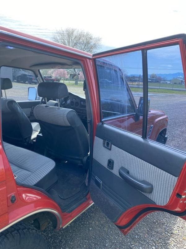 Open red car door showing interior seats and door panel.