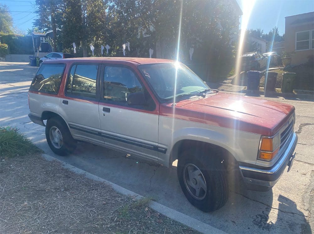 A red and silver SUV parked on a sunny day.