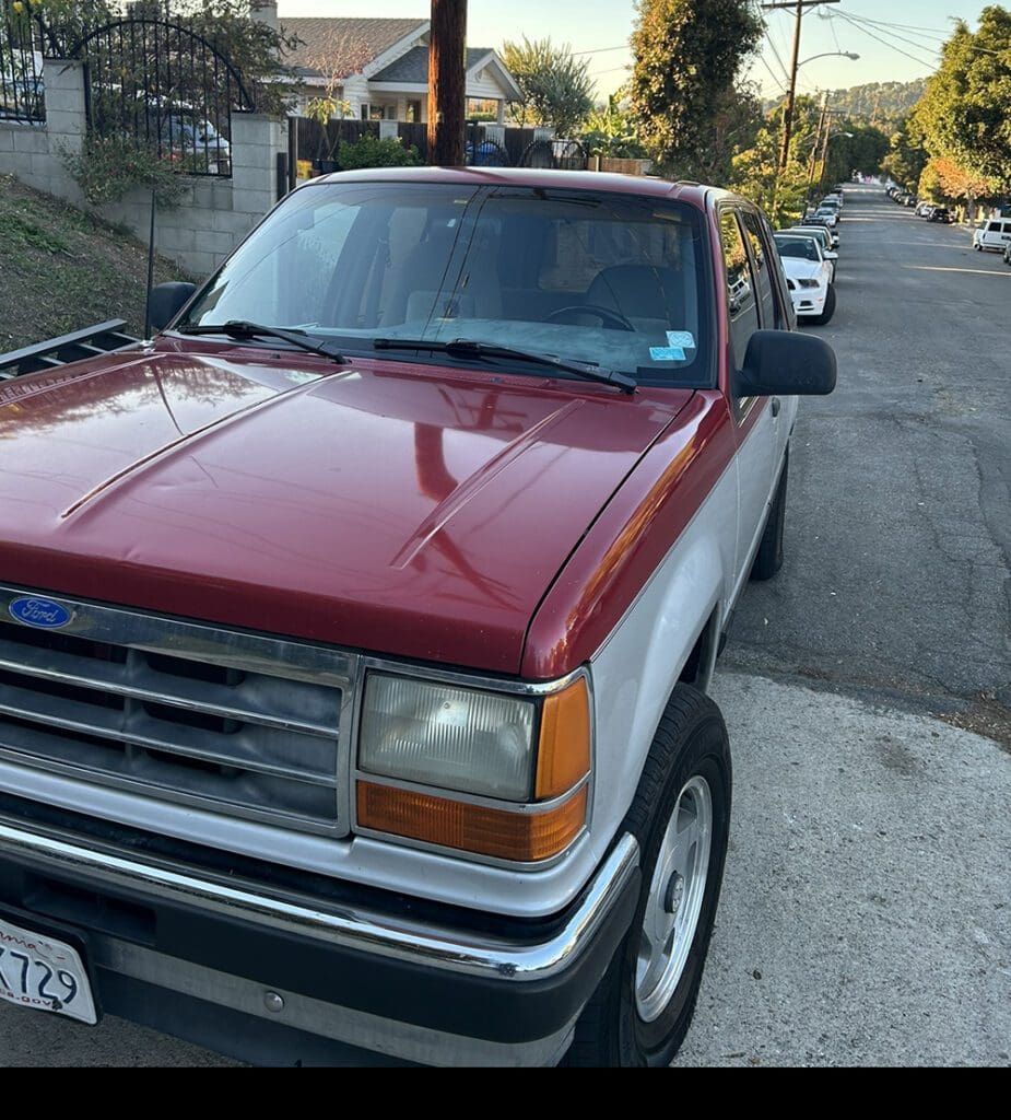 Two-tone red and silver pickup truck parked on a residential street.