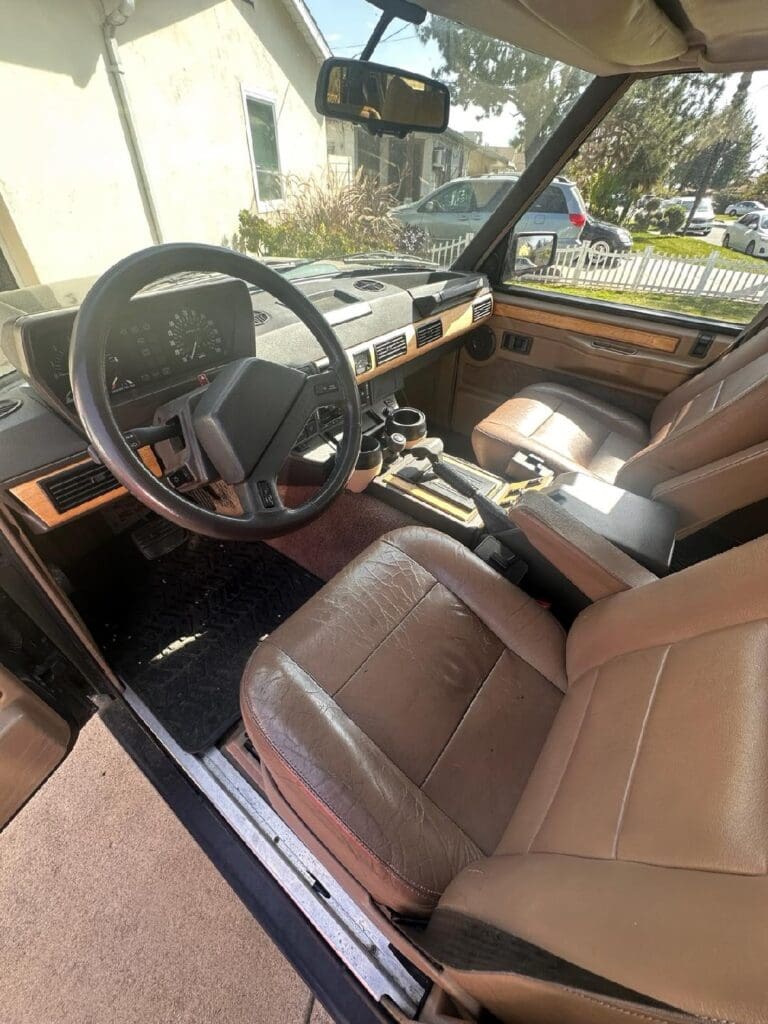 Classic car interior with brown leather seats and wooden dashboard accents.