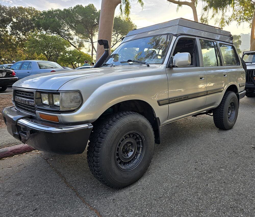 Silver Toyota Land Cruiser parked outdoors with rugged tires and lifted suspension.
