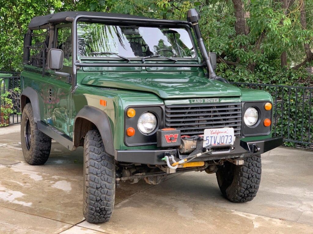 Green off-road vehicle parked near trees.
