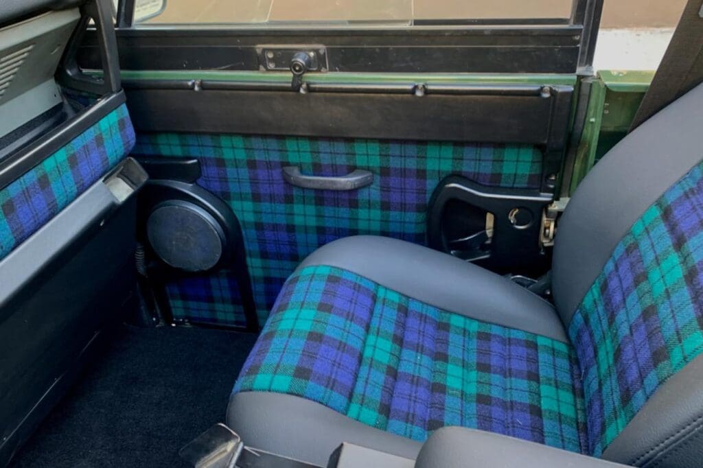 Car interior with blue and green tartan upholstery on seats and door panels.