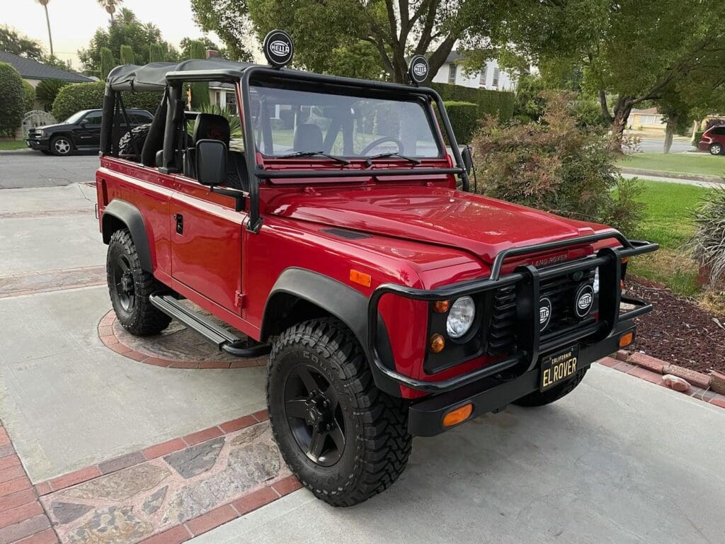Red off-road vehicle parked outdoors with black wheels and a rugged design.